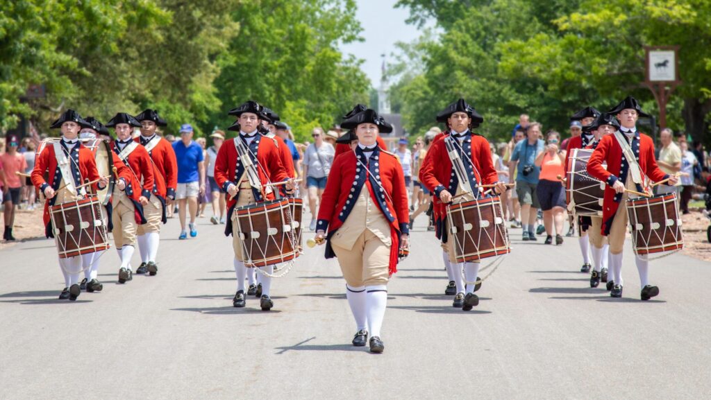 A fife and drum corps in red coats marching through Colonial Williamsburg