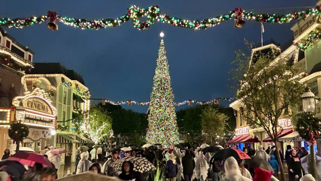 Disneyland Main Street at night decorated for the holidays on a rainy night