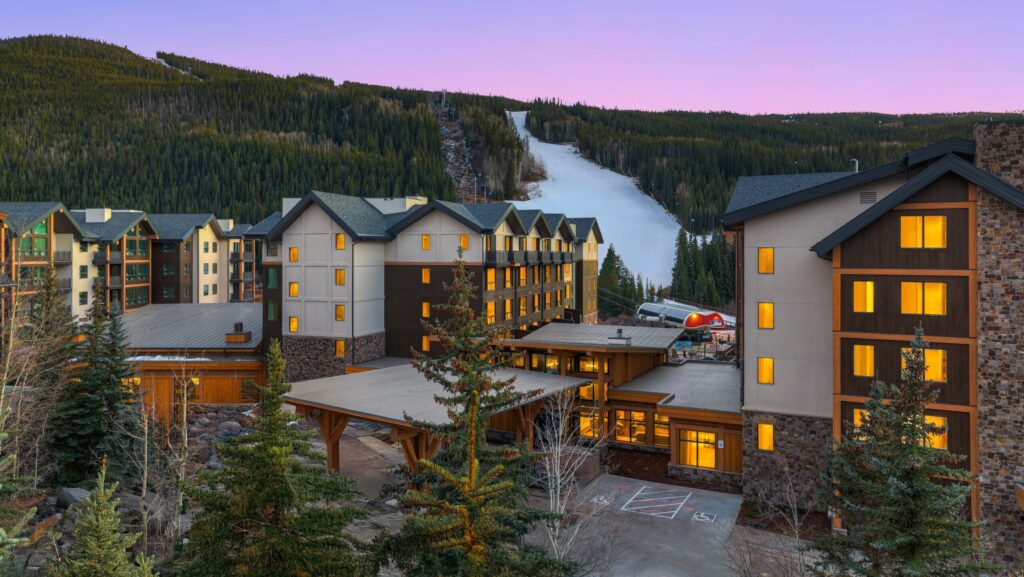 An evening view of Kindred Resort with a snowy ski slope behind it