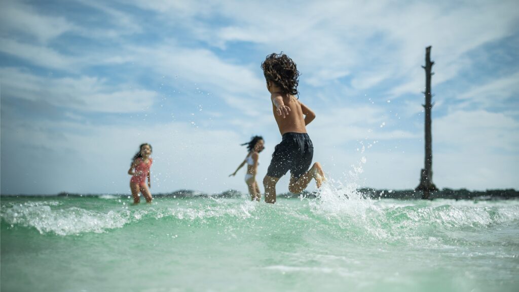Three kids running in the water at the beach in Destin-Fort Walton Beach, Florida.