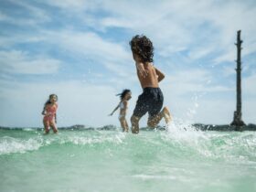 Three kids running in the water at the beach in Destin-Fort Walton Beach, Florida.