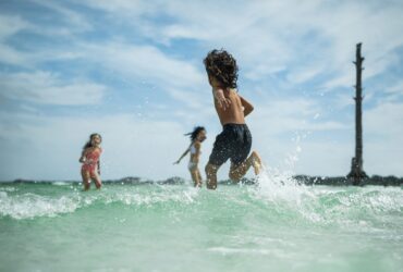 Three kids running in the water at the beach in Destin-Fort Walton Beach, Florida.