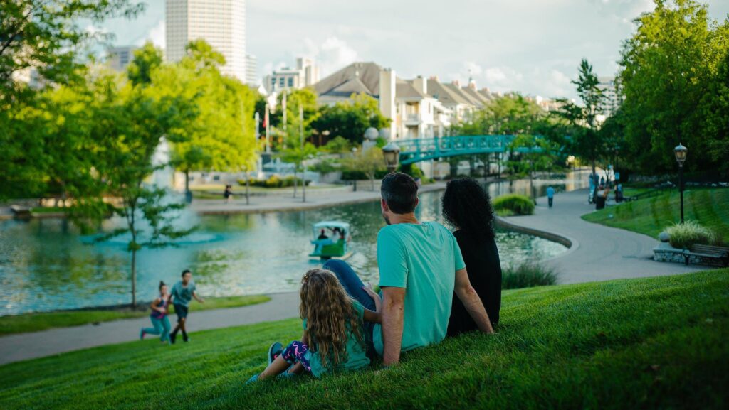 A family sitting on the grass looking at the canal in downtown Indianapolis