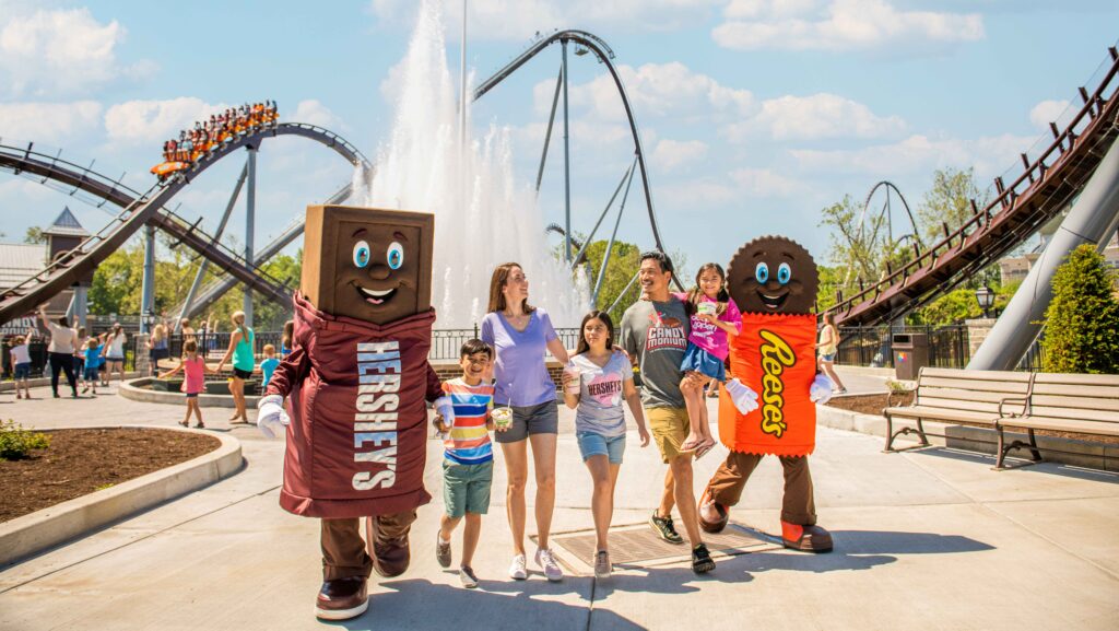 A family walking with Hershey Bar and Reese's Peanut Butter Cup characters at Hersheypark
