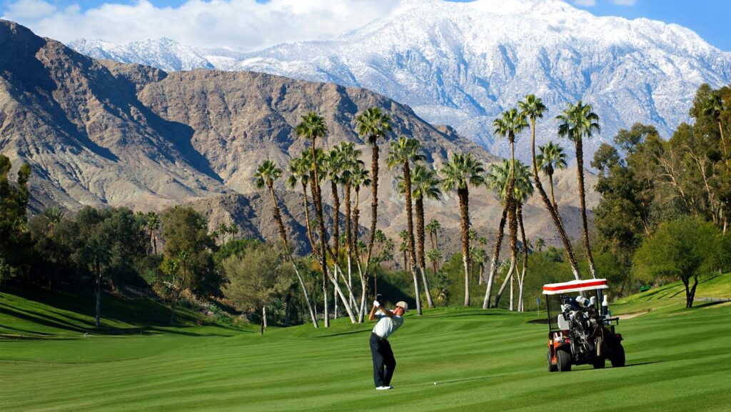 A golfer on a course in Palm Springs with mountains in the distance 