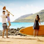 A family in the beach with a paddleboard at The Royal Sonesta Kauai Resort Lihue