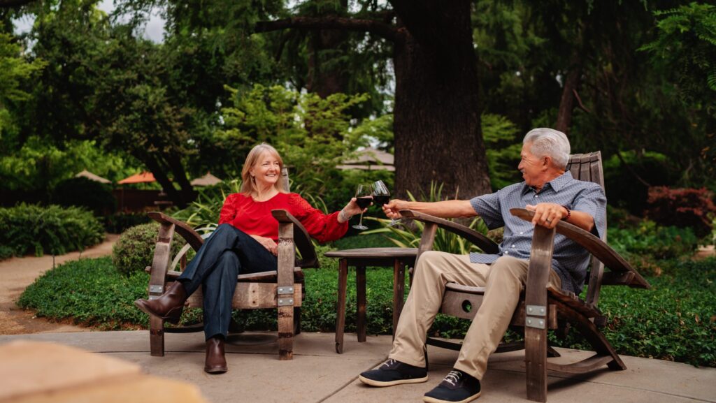 Pasangan menyeruput anggur di kursi aiderondack