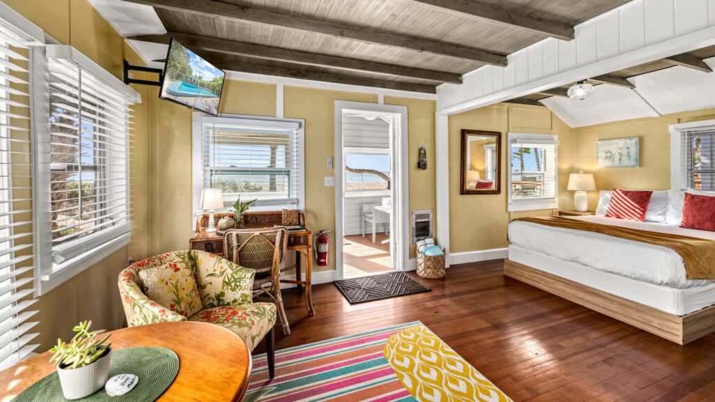A guest room at Manasota Beach Club with a wood paneled ceiling and a view out to the beach