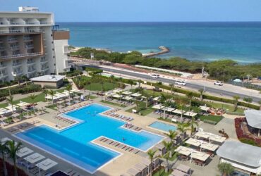 View from a guest room at the Embassy Suites Aruba Resort looking out over the pool toward the beach