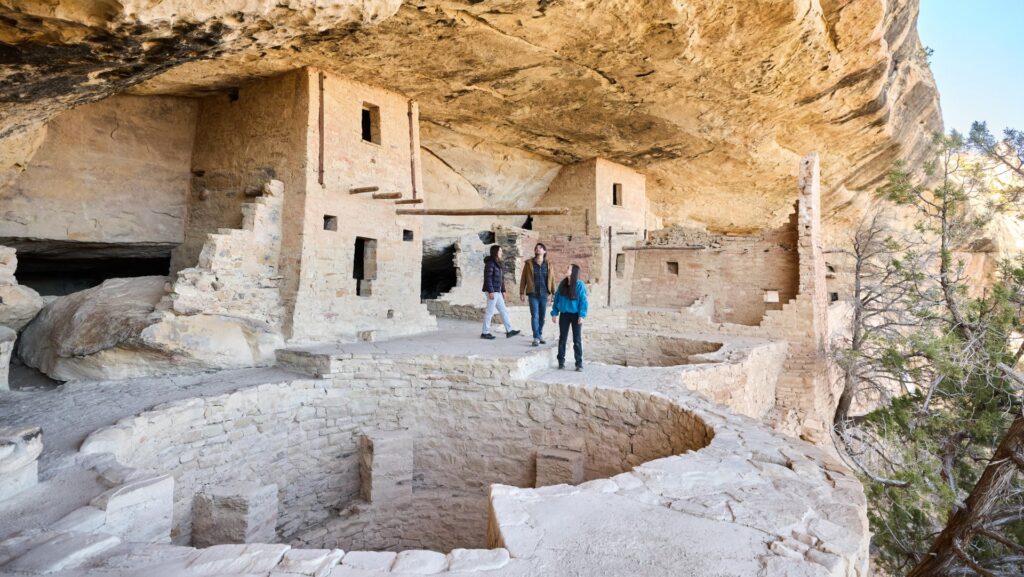 Three people looking at the Balcony House on the Trail of the Ancients at Mesa Verde
