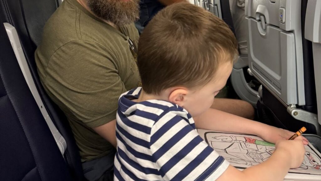 little boy coloring on airplane tray table