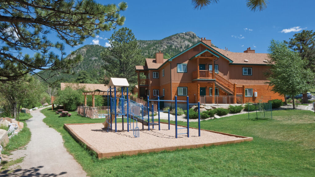 Pemandangan taman bermain dan beberapa penginapan di WorldMark Estes Park dengan pegunungan di kejauhan