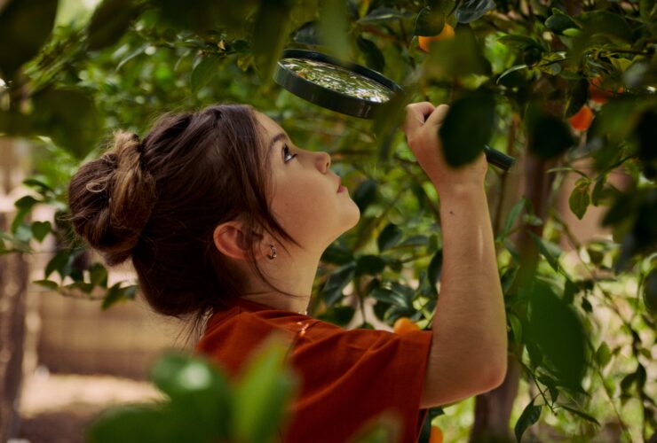 A girl looking at vegetation through at magnifying glass