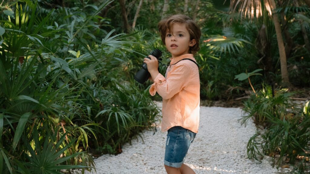 A little boy with binoculars exploring the landscape around Conrad Tulum Riviera Maya