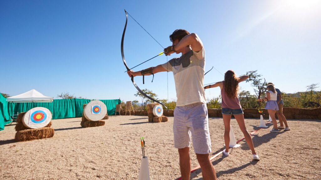 Teens with bows and arrows aiming at targets in an rchery activity
