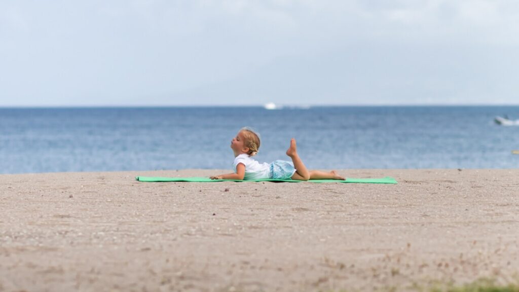 A little girl doing yoga on the beach