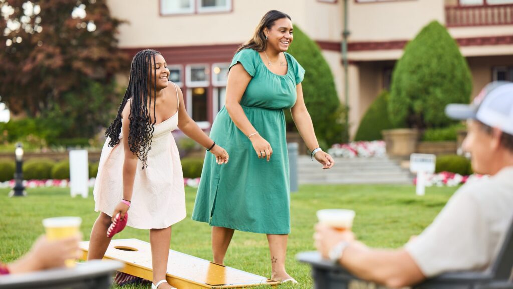 A woman and girl playing cornhole on the Front Lawn art Ocean Edge Resort