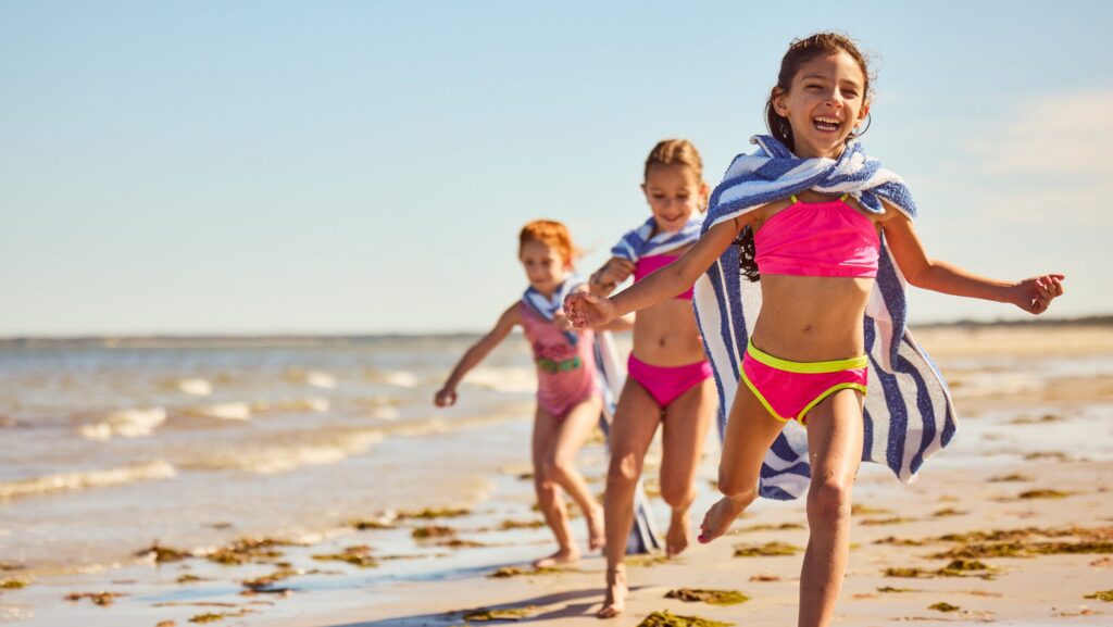 Three kids running on the beach at Ocean Edge Resort